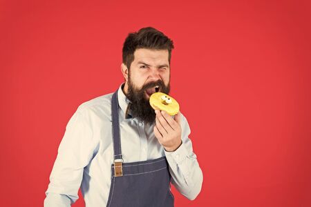 Hipster bearded baker hold glazed donut on red background. Cafe and bakery concept. Sweet donut from...