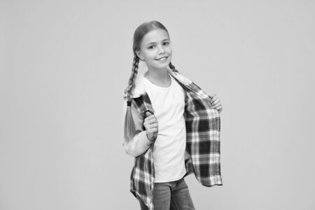 Casual style. Little girl yellow background. Good mood concept. Positive vibes. Sincere emotions. Cute braided girl. Kid long hair. Small girl checkered shirt. Happy international childrens dayの写真素材