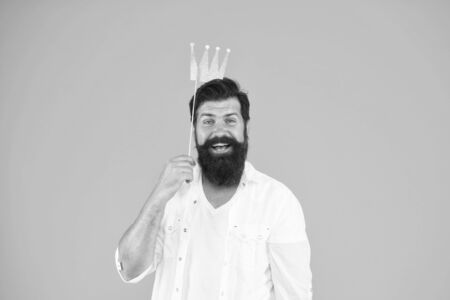 Handsome bearded guy king. King of party. Costume party. Holiday carnival celebration. Birthday boy. Guy in yellow background posing with booth props. Photo booth fun. Bearded man king costume partyの写真素材