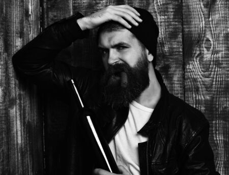 Bearded brutal caucasian hipster holding bottle and smoking cigarの写真素材