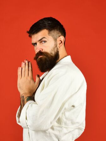 Man with beard in white kimono on red background