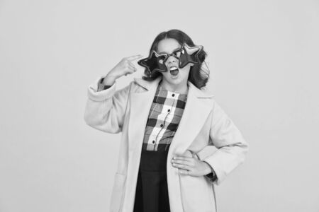 Carnival costume famous celebrity. Rock star. Girl confident cool kid wear star shaped sunglasses. Star concept. Fame and popularity. Party holiday celebration. Cheerful girl wear eyeglasses for funの写真素材