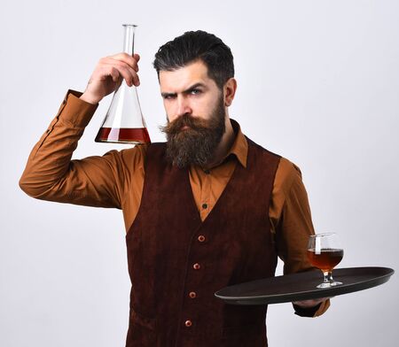 Barman in vintage suede leather waistcoat serves scotch or brandy.