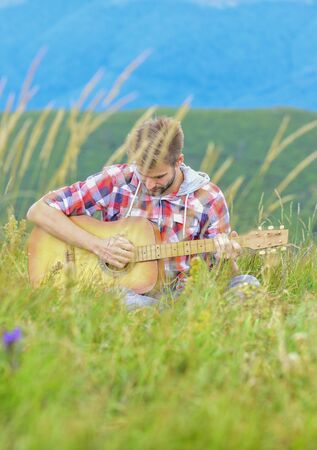Inspiring environment. Man musician with guitar on top mountain. Inspired musician. Summer music festival outdoors. Playing music. Silence of mountains and sound of guitar strings. Hipster musician.の写真素材