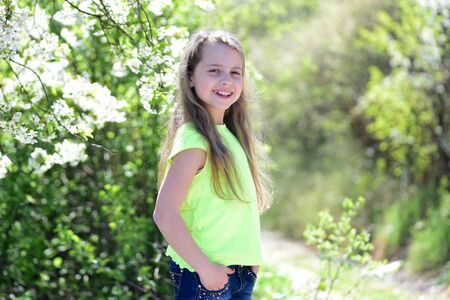 Schoolgirl walks outside near blooming trees. Childhood and natural beautyの写真素材