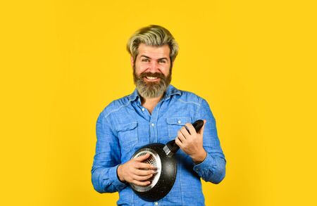 Professional kitchenware. Nonstick pan for frying. Enameled cooking vessels. Man hold pan. Frying meal. Healthy food. Bearded hipster preparing breakfast. Perfect for pancakes. Frying without oilの写真素材