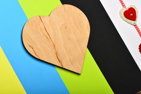 Valentines day and love concept. Handmade decorations on colourful striped background. Checked ribbon with red and white hearts beaded on it. Heart shaped piece of wood.の写真素材