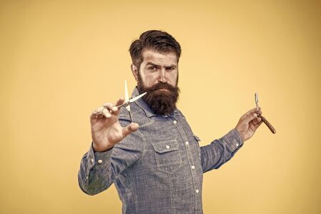 Retro and old-fashioned. Bearded man hold retro razor and scissors. Professional barber with retro tools at work. Retro barbershop specialized in classic cuts, vintage filterの写真素材