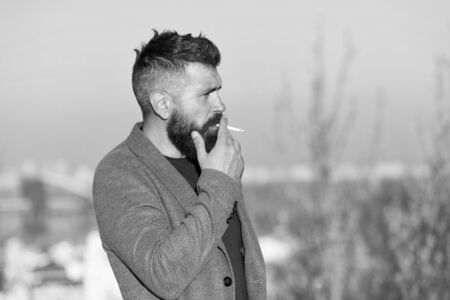 Cigarette tobacco harmful health influence. Smoking aesthetics. Smoking devices concept. Bearded hipster smoking outdoors. Device hide conceal smell of smoke. Handsome man smoke flying out of mouthの写真素材