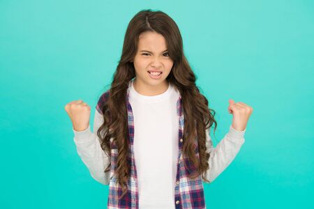 Inner energy. Little girl flex arms blue background. Small girl with long hair show strength. Fitness. Beauty and health. Childhood and girlhood. Feminism concept. Future is female. Strong girlの写真素材