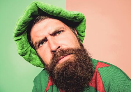 Who is there. Picky man looking at camera. Bearded elf. Winter carnival. St Patricks day. Hipster with beard wearing green costume for party. Christmas elf. Elf concept. Traditions or customsの写真素材