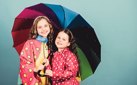 cheerful hipster children, sisterhood. rain protection. Rainbow. autumn fashion. happy little girls with colorful umbrella. family bonds. Little girls in raincoat. Important part of campingの写真素材