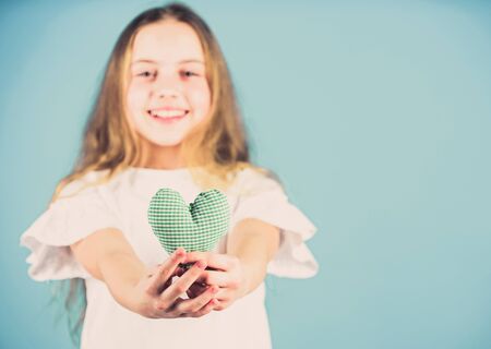 Love concept. Girl cute child show heart toy. Heart symbol of love. Romantic feelings. Kid adorable girl happy face play heart blue background. Celebrate valentines day. Love heart holiday decorの写真素材
