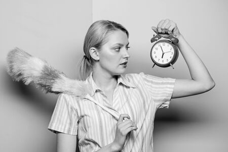Perfectionism concept. Woman hold dust brush alarm clock. Everything must be perfect. Girl perfectionist. Perfectionist complex. Obsessive compulsive disorder. Cleaning time. Obsessed perfectionistの写真素材