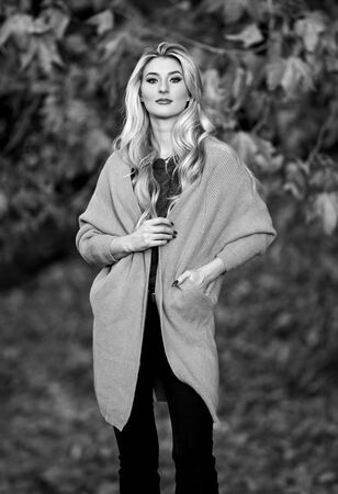 Girl adorable blonde posing in warm and cozy outfit autumn nature background defocused. Woman walk sunset time. Cozy casual outfits for late fall. Cozy and comfortable. Cozy outfit ideas for weekendの写真素材