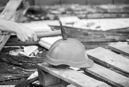 Material strength. Building construction. Professional hard hat. Engineer architect repairer safety accessory. Helmet or hard hat. Hammer knocking helmet close up. Test concept. Protective helmet.の写真素材