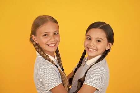 happy friends on yellow background. fashion beauty. childhood happiness. sisterhood concept. small girls in retro school uniform. children in vintage style. old school fashion. we are togetherの写真素材