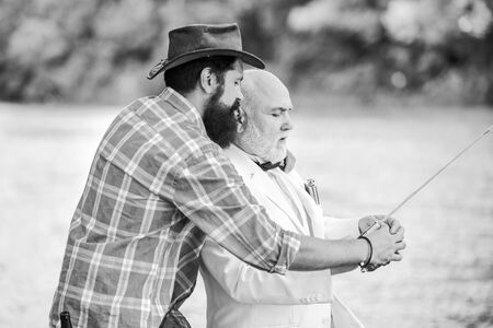 Bearded man and elegant businessman fish together. Learn to fish. Fish with companion who can offer...