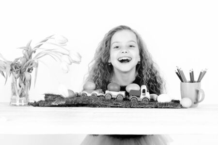 happy easter girl with colorful eggs in lorry, pencils, tulipsの写真素材