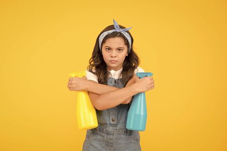 Household as battle. Girl cute kid cleaning around. Protect sensitive skin. Kid cleaning at home. On guard of cleanliness. Mist sprayer for wiping dust. Girl ready for cleaning. Who is on duty todayの写真素材