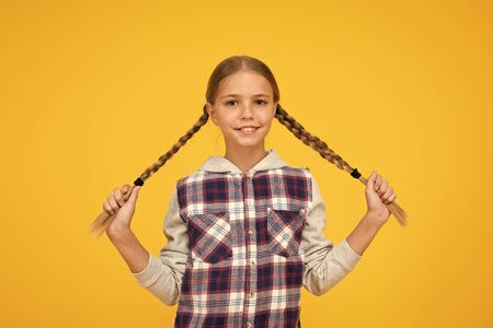Kid long hair. Small girl checkered shirt. Happy international childrens day. Little girl yellow background. Good mood concept. Positive vibes. Sincere emotions. Having fun. Cute braided girlの写真素材