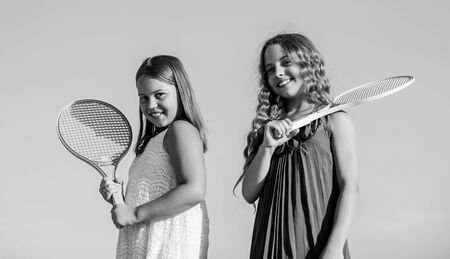 Sport is our life. small girls with tennis racquet. summer sport activity. energetic children. happy and cheerful. sporty game playing. summer games. play tennis. childhood happiness and sisterhoodの写真素材