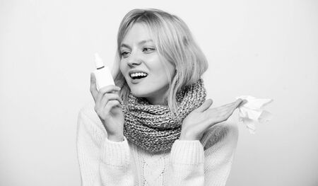 Happy to breathe again. Sick woman spraying medication into nose. Treating common cold or allergic rhinitis. Cute woman nursing nasal cold or allergy. Unhealthy girl with runny nose using nasal sprayの写真素材
