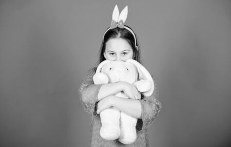 Get in easter spirit. Happy childhood. Bunny ears accessory. Lovely playful bunny child hugs soft toy. Have blessed Easter. Bunny girl with cute toy on blue background. Child smiling play bunny toyの写真素材