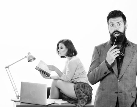 Too smart to fall for this. Bearded man in smart casual wear with sexi coworker. Smart businessman and pretty secretary in office. Smart man holding glasses while sexy woman working in backgroundの写真素材