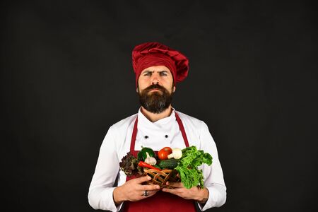 Cook with proud face in burgundy uniform holds vegetablesの写真素材
