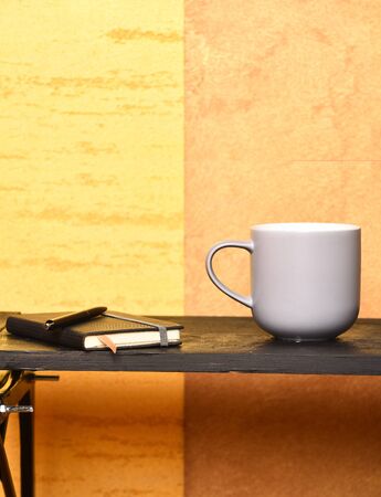 Tea or coffee on black table in modern interior. Good morning and cozy workplace concept. Notebook...