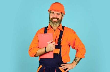man in overalls. Structural plan safety. work operation concept. looking project folder. blueprint in folder. make notes in clipboard. portrait of engineering man. construction worker holding folderの写真素材