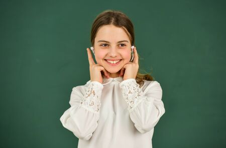 favorite tune. home schooling online education. back to school. small girl in headphone at blackboard. listening audio book. free ebook. cool girl in headphones listening to music. e-learning conceptの写真素材