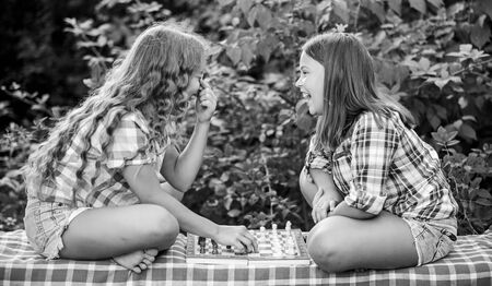 two concentrated girls play chess. chess playing sisters. skilled children. turn on your brain. make the brain work. early childhood development. worthy opponents. develop hidden abilitiesの写真素材