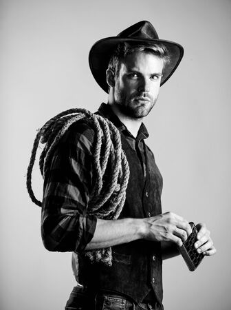 have a drink. wild west rodeo. man in hat drink whiskey. man checkered shirt on ranch. cowboy with lasso rope. Western. Vintage style man. Wild West retro cowboy. western cowboy portraitの写真素材
