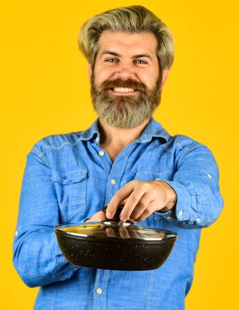 Cooking food concept. Hold frying pan. best quality. bearded cook portrait with kitchen tools. bearded man hold cooking pan. cook preparing food in kitchen. husband on kitchen. selective focusの写真素材