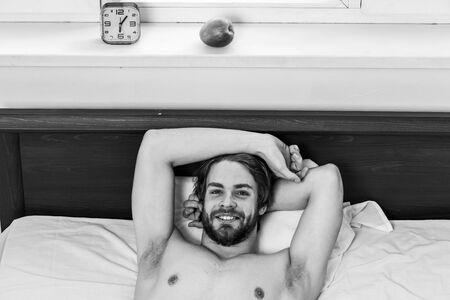 Stretch after wake up in the morning. Bare feet of a man peeking out from under the cove. Sleepy guy waking up early after hearing alarm clock signal on monday morning.の写真素材