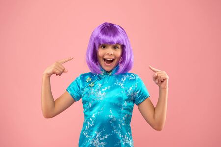 I love my new hair. Little girl pointing at violet hair. Happy child wear fancy hair wig. Haircut...
