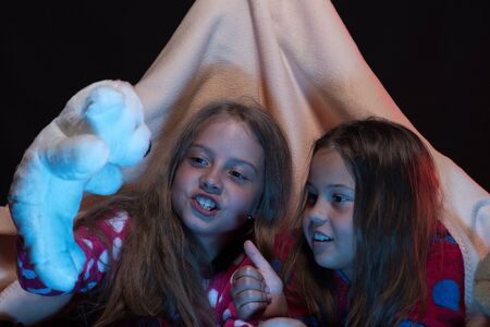 Girl friends playing with toys in blanket tentの写真素材
