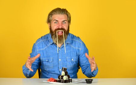 sushi and ginger with chopsticks. Japanese cuisine. Traditional food in Japan. Chief meal Fast service. asian meal. sushi roll dish take away. Sushi delivery. happy man eat sushiの写真素材