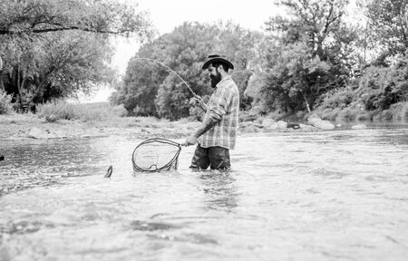 Fishing provides that connection with whole living world. Find peace of mind. Bearded fisher catching trout fish with net. Fishing is astonishing accessible recreational outdoor sport. Fishing hobbyの写真素材