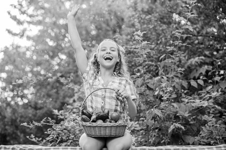 Eat healthy. Summer harvest concept. Gmo free. Healthy food concept. Girl cute smiling child living healthy life. Healthy lifestyle. Kid hold basket with vegetables nature background. Eco farmingの写真素材