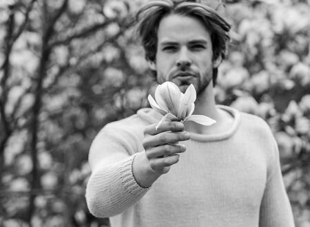 Floral cosmetics concept. Hipster enjoy blossom aroma. Unshaven man magnolia bloom. Man flowers background defocused. Hairdo styling. Spring beauty. Botany nature. Male beauty. Hair care and beautyの写真素材