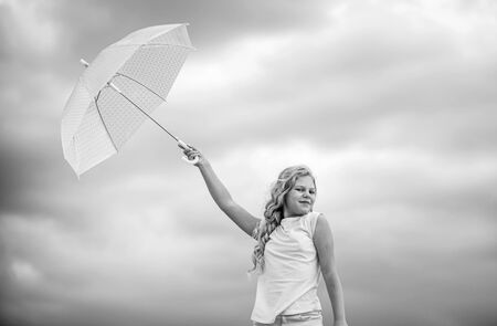 Freedom and freshness. Happy childrens day. Enjoying ease. Carefree child outdoors. Weather forecast. Ready for any weather. Weather changing. Fresh air. Girl with umbrella cloudy sky backgroundの写真素材