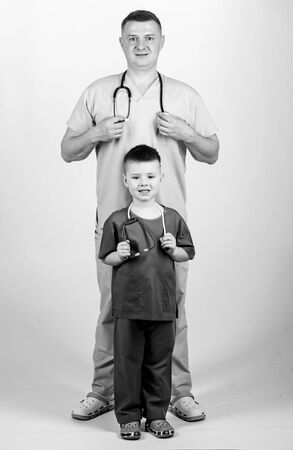 Future profession. Want to be doctor as dad. Cute kid play doctor game. Family doctor. Pediatrician concept. Father doctor with stethoscope and little son physician uniform. Medicine and health careの写真素材