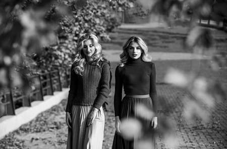 forest foliage. sunny day with fallen leaves. fall fashion season. Pleated trend. girls in corrugated skirt and sweater. female beauty. real femininity. autumn women outdoor. girl friend walk in parkの写真素材