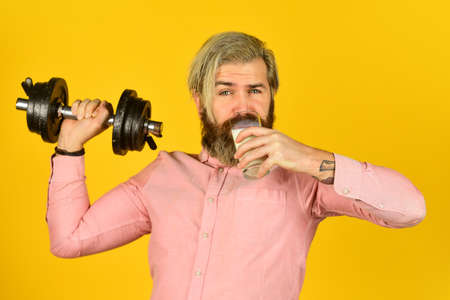 Exercise in gym. Milk good nutrients. Amount of fat. Vitamins for muscles. Sportsman hold dumbbell and glass of milk. Protein diet. Protein cocktail. Source of calcium. Bearded man drink milkの写真素材