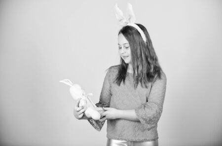 Little baby holding Easter bunny and egg. Cute child with Easter bunny rabbit bringing egg. Small kid with bunny and colored egg on Easter dayの写真素材