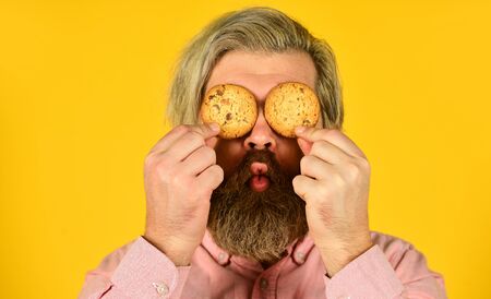 Obsessed with pastry. Recipe homemade cookies. Happy hipster eat cookie dessert. Sweet cookies. Sweet Tooth concept. Cookies on his mind. Bearded man hold cookies on eyes. Yummy delicious treatsの写真素材