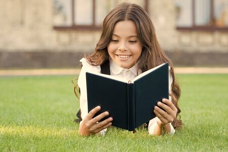 Who needs rest when theres another book to be read. Adorable small child read book on green grass. Cute little girl relax reading book outdoor. Seize every day with new book. School and knowledgeの写真素材